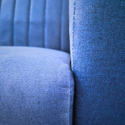 Navy blue fabric two-seater sofa on rent, featuring a sleek modern design with textured upholstery in a comfortable living room setting.