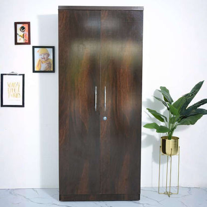 Wooden wardrobe with two doors in a room with a plant and framed pictures on the wall.