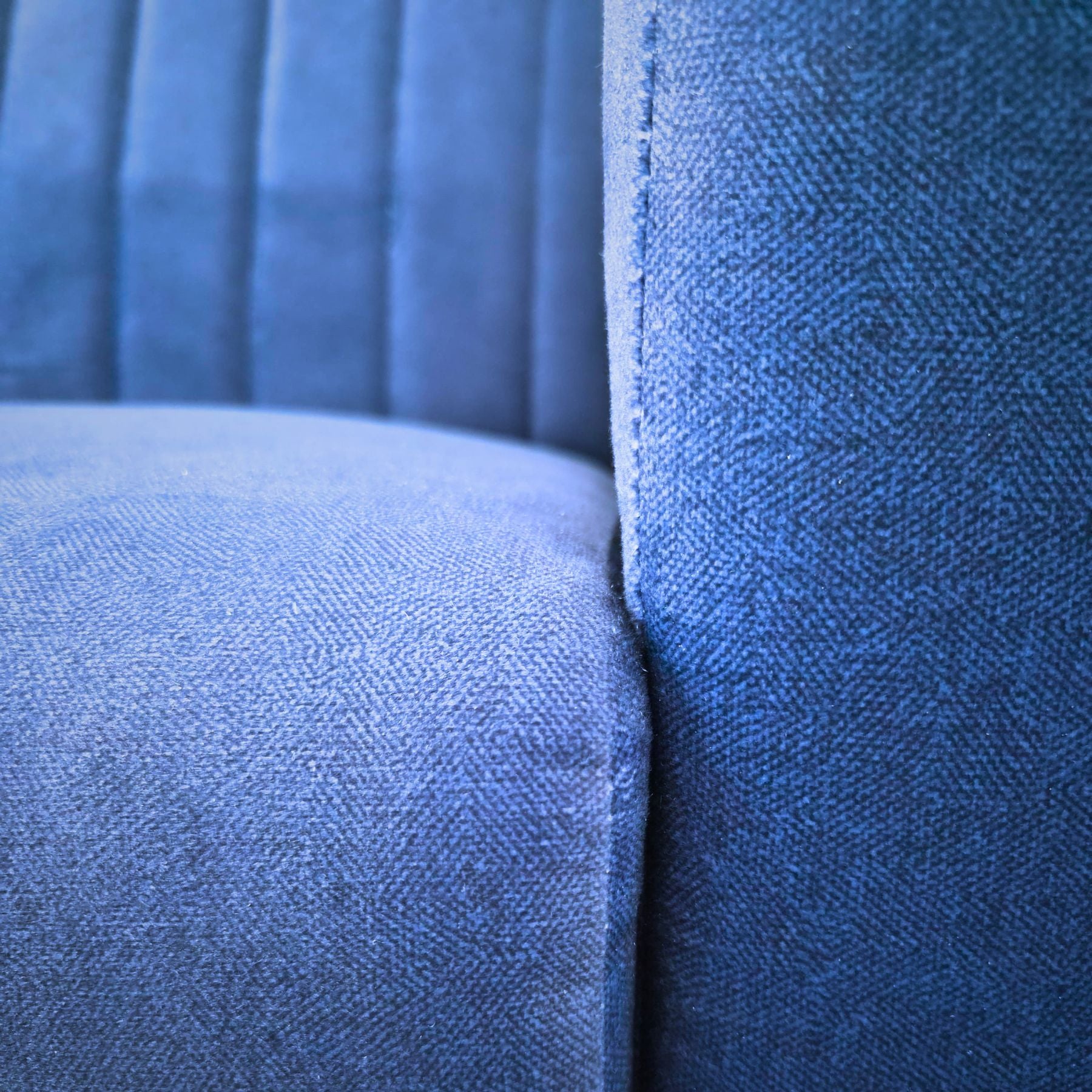 Navy blue fabric two-seater sofa on rent, featuring a sleek modern design with textured upholstery in a comfortable living room setting.
