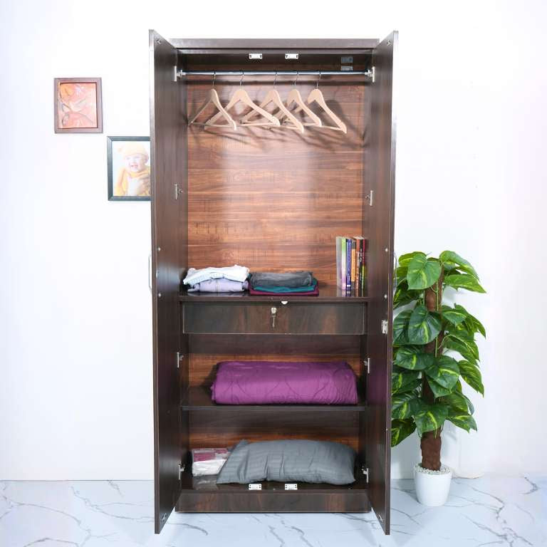 Wooden wardrobe with clothes and a plant in a room.