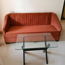 A mocha-brown velvet three-seater compact sofa with vertical channel tufting, ideal for a compact living room setting with a glass-top coffee table in front. Available on affordable monthly rent with free delivery in pune kharadi wagholi Hadapsar Amanora Magarpatta keshav nagar Viman Nagar Aundh Baner Balewadi Hinjewadi Wakad ravel punawale.