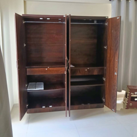 A large dark brown wooden double-door wardrobe or cabinet with both doors open, showing interior shelves and hanging rails, photographed in a room with light-colored walls and floor. Available on affordable monthly rent with free delivery in pune kharadi wagholi Hadapsar Amanora Magarpatta keshav nagar Viman Nagar Aundh Baner Balewadi Hinjewadi Wakad ravel punawale.